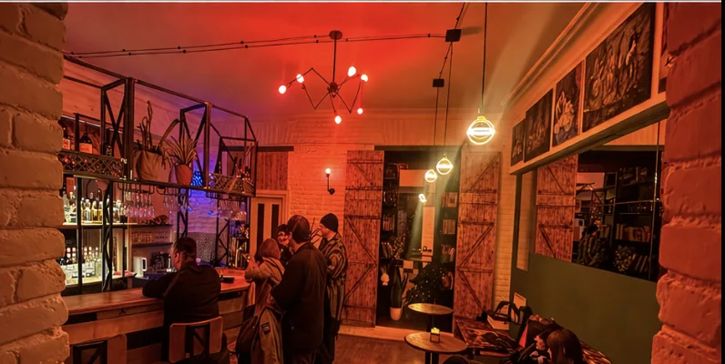 Inside Real Bar: warm neon glow, exposed brick and a busy crowd in Sololaki, Tbilisi